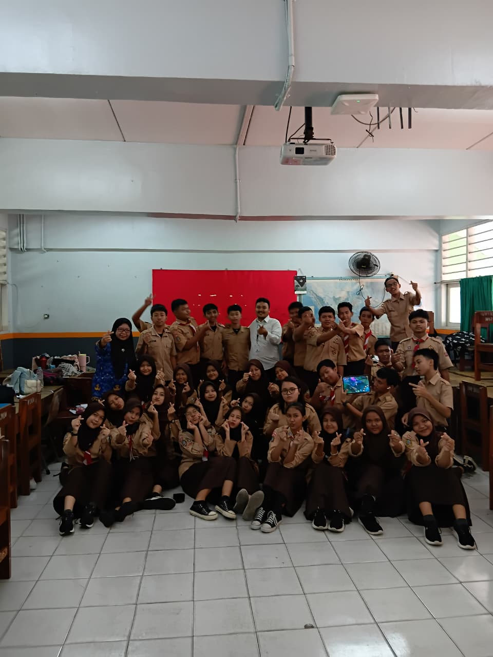 Foto bersama di ruang kelas dengan murid mengenakan seragam pramuka.