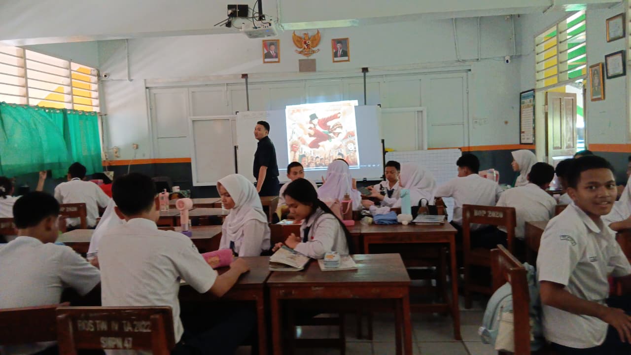 Murid duduk berkelompok di kelas dengan media proyeksi di depan.